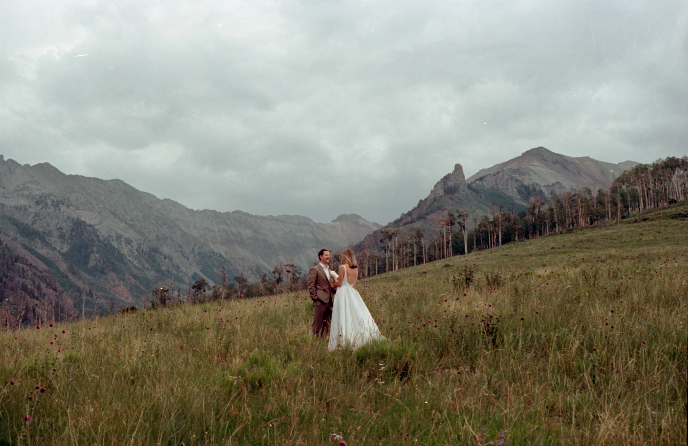 Couple exchanging vows on Last Dollar Road, surrounded by rolling meadows, aspen trees, and breathtaking mountain views in Telluride, Colorado.